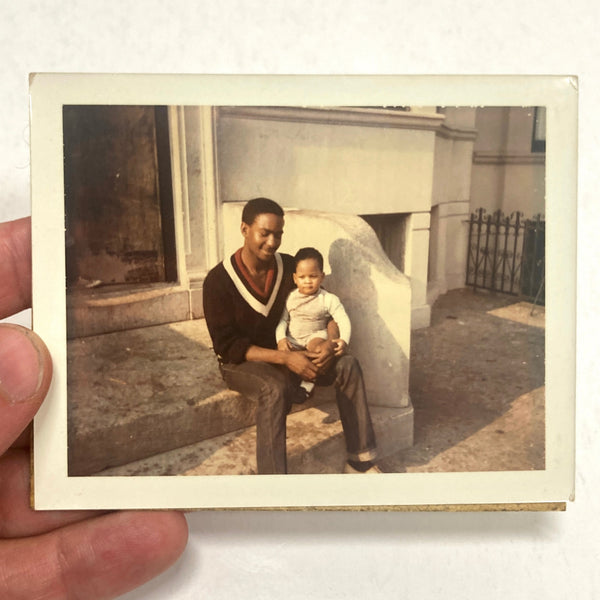 Photograph of Handsome African-American Man Holding Baby Seated on Building Stoop